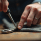 Main nettoyant une clé hex avec un chiffon sur un plan de travail en bois